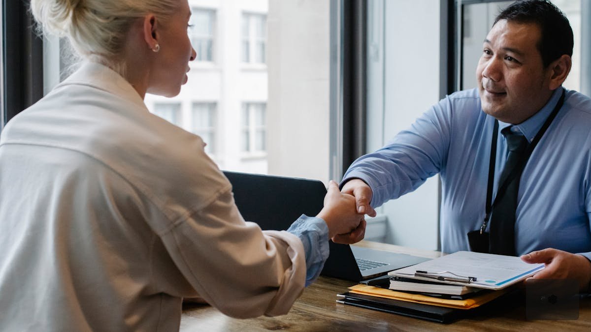Law firm associate pointing at contract clause highlights on computer monitor while senior partner takes notes