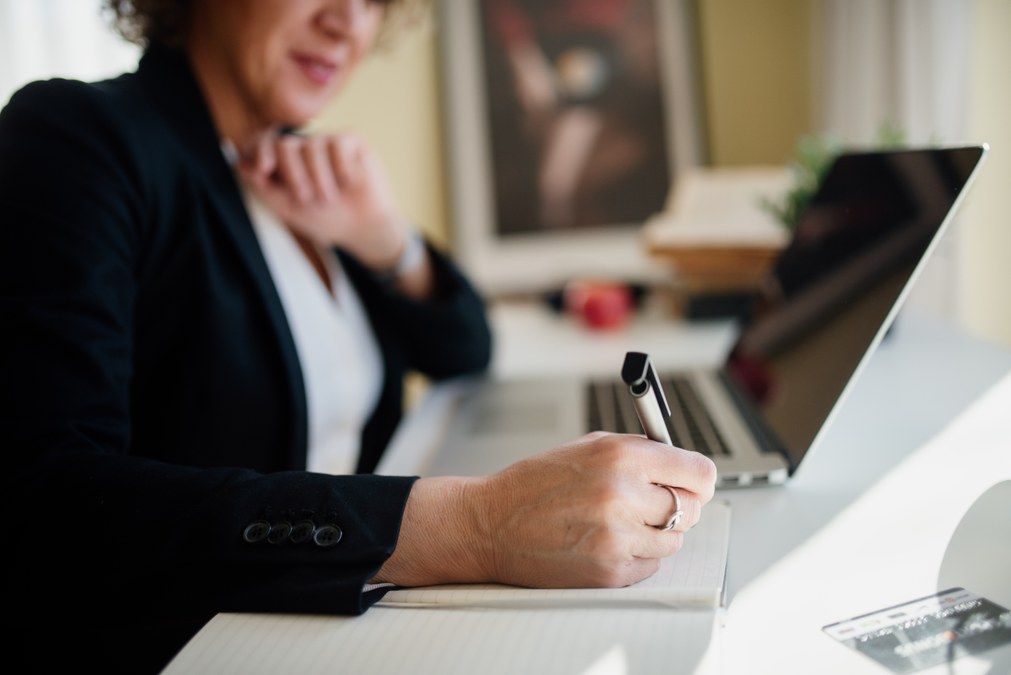 Wealth advisor presenting quarterly review materials to clients in bright conference room with charts and tablets visible